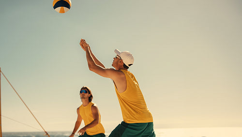 Professional australian volleyball team soaring in mid-air at coastal beach tournament