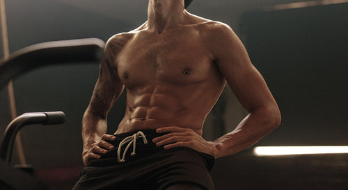 Fit man with muscular abs on bike at gym