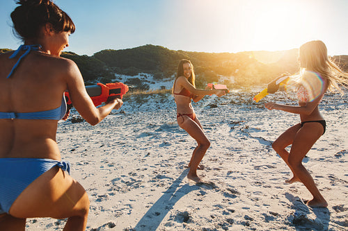 Girls with water pistols playing on the beach