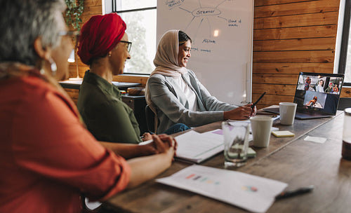 Happy female entrepreneurs attending a video conference in an of