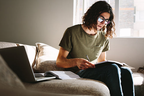 Male student sitting with books on a couch
