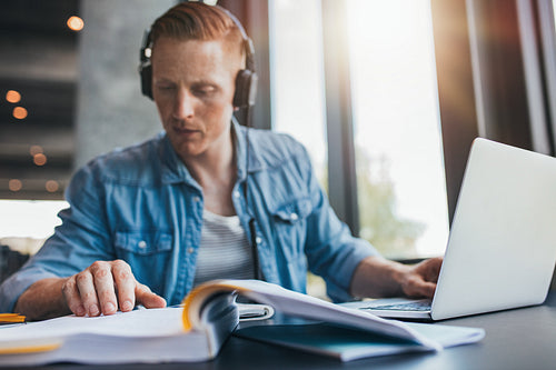 Young man studying in library reading book