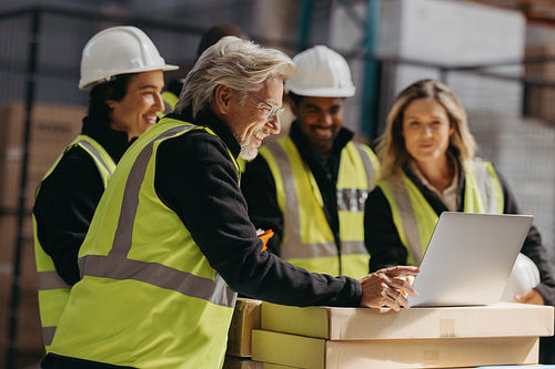 Successful warehouse team watching a presentation on a laptop