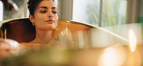 Brunette woman lying comfortably in a bathtub