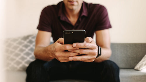 Man looking at mobile phone sitting at home