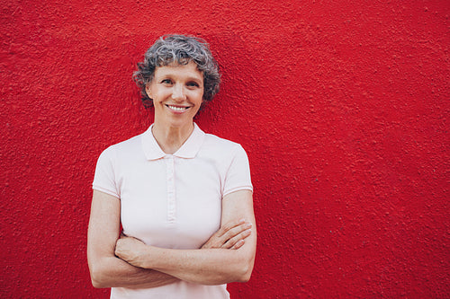 Portrait of happy mature woman against red wall