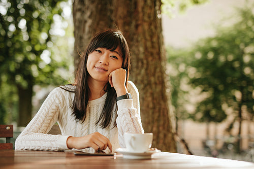 Happy chinese woman at cafe table with digital tablet