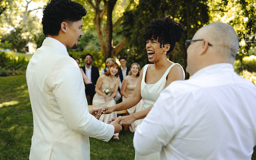 Joyful outdoor wedding ceremony with bride and groom exchanging smiles and vows