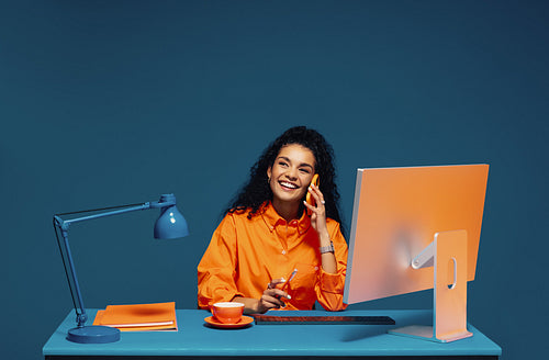 Employee using smartphone and computer in color blocking studio shot