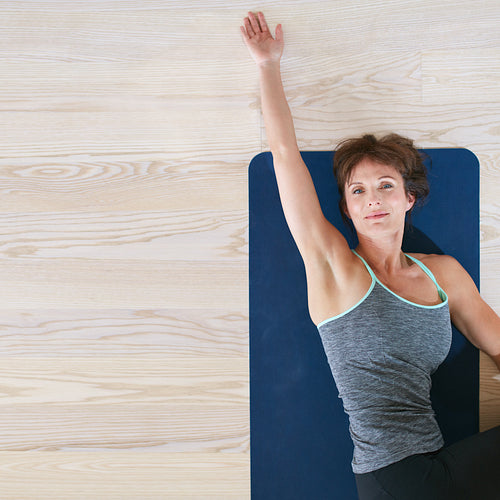 Woman lying and stretching on exercise mat