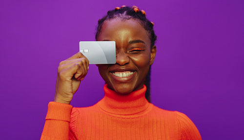 Contactless payment with a cheerful woman holding her bank card on a vibrant purple background
