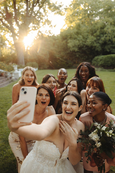 Bride taking a selfie with bridesmaids during wedding celebration in a garden