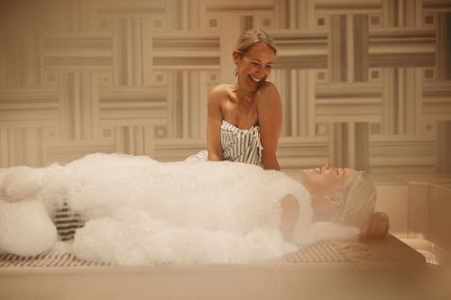 Mature woman and younger woman enjoying wellness in a Turkish bath with bubbles