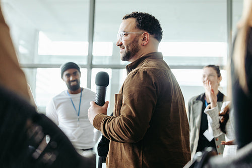 Confident business owner leading a team training session with a microphone in a modern office setting, promoting leadership and teamwork