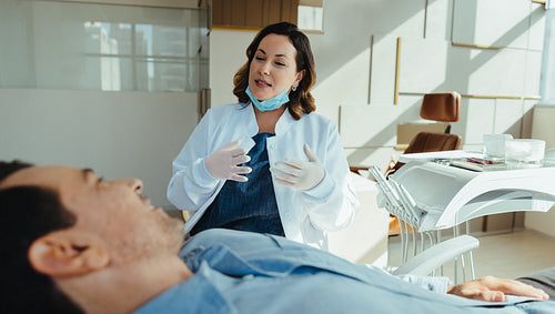 Dentist consulting with patient in modern dental chair before examination