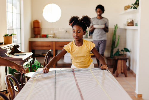 Young girl setting the breakfast table with a cloth at home