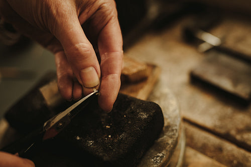 Female jeweler cutting small pieces of metal 