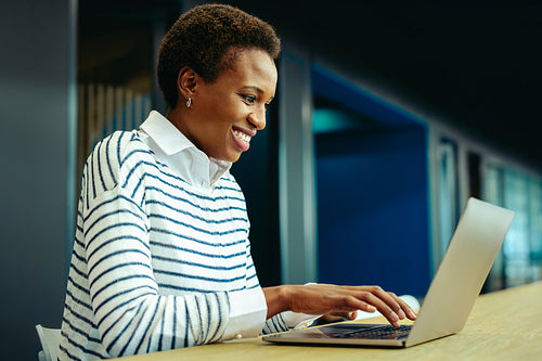 Smiling woman working on laptop in modern office setting