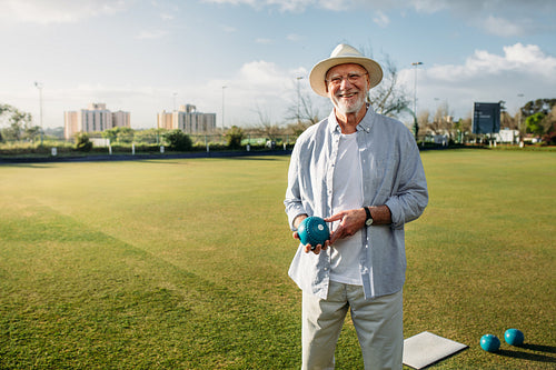 Senior man playing boules in a lawn