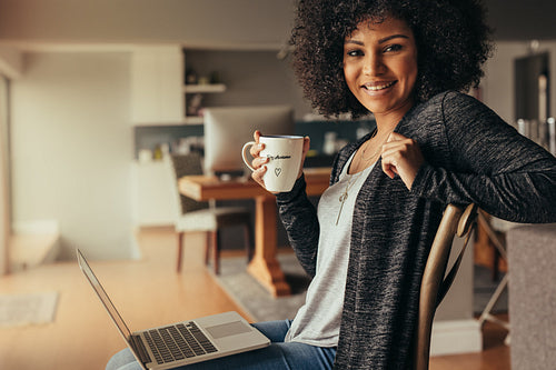 Beautiful woman at home with laptop and having coffee