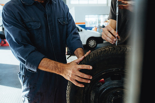 Technicians measuring the depth of tire tread instrument