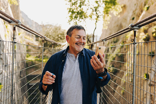 Happy senior man having a video call while hiking outdoors