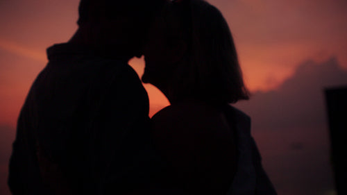 Romantic couple silhouettes at sunset toasting with champagne