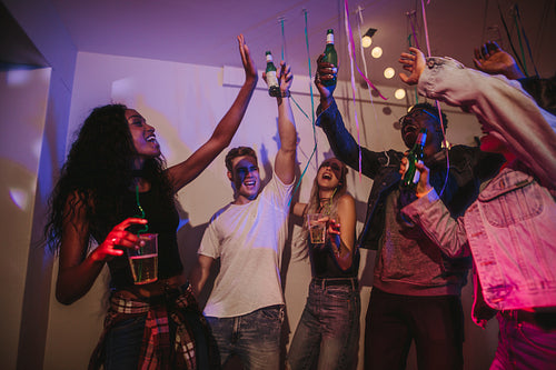 Friends dancing and raising their drinks at a party