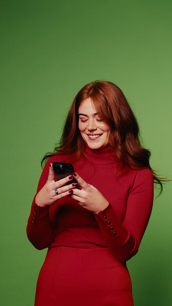 Happy woman in red dress using phone on green screen background