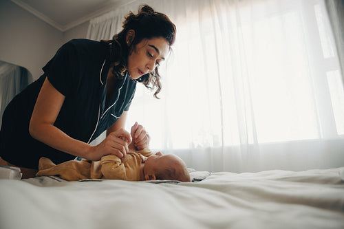 Mother lovingly interacts with baby son on bed by window