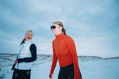 Women running together in winter snow during outdoor fitness training