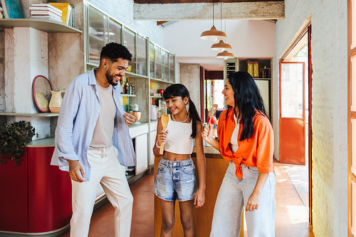 Latino family bonding while playfully singing and laughing in modern kitchen
