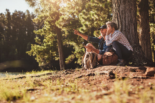 Mature sitting near a lake using compass