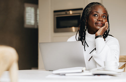 Senior businesswoman looking away thoughtfully in her home office