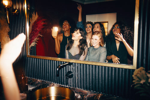 Group of friends enjoying a joyful moment together in stylish nightclub powder room