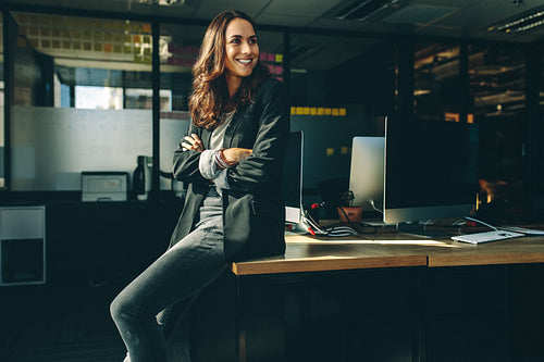 Smiling businesswoman sitting on her desk