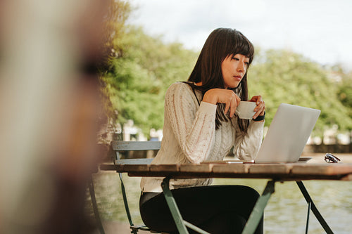 Female having coffee at cafe and using laptop 