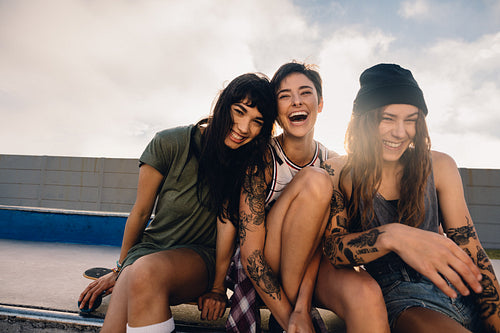 Three smiling girls hanging out at skate park