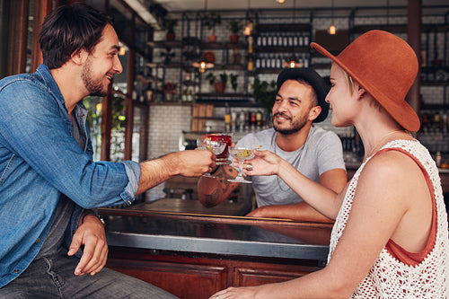 Young friends toasting drinks at cafe