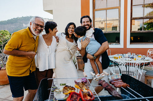 Happy family enjoying a backyard churrasco together on a sunny day