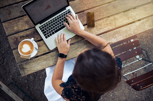 Woman working on her laptop at outdoor cafe