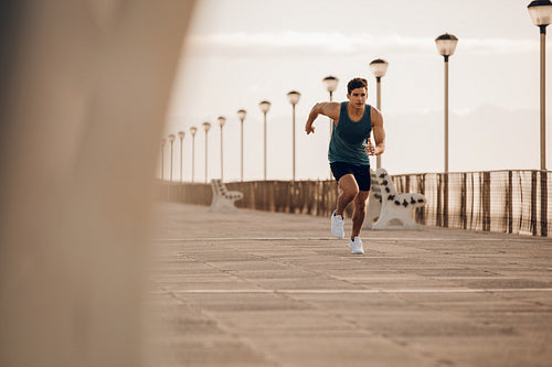 Fit young man running fast on the promenade