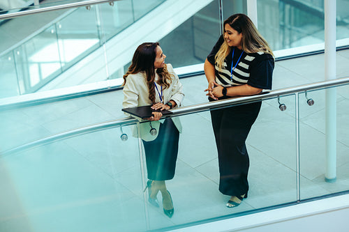 Two coworkers engaged in casual conversation on a modern office stairway