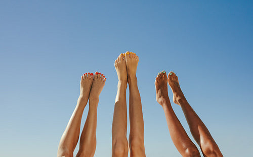 Close up of legs of three women raised up in the air