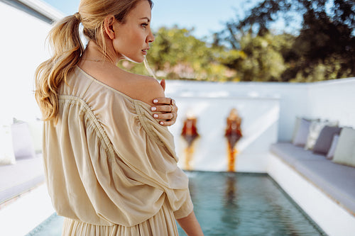 Gorgeous woman taking her dress off in front of a pool