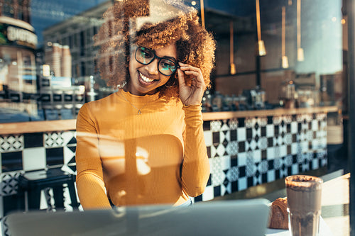Smiling woman sitting at a cafe looking at laptop 