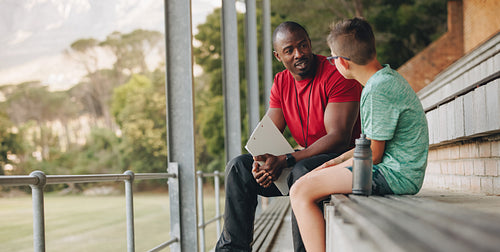 School coach talking a young student while sitting outside