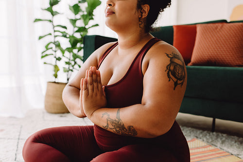Plus size woman practicing yoga meditation at home