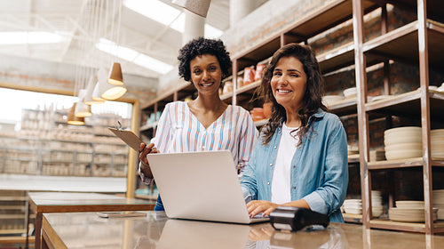 Cheerful young ceramists smiling at the camera in their shop