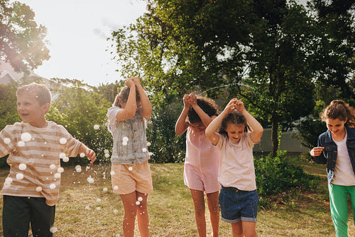 Children playing outdoors with water balloons in a bright and joyful summer setting
